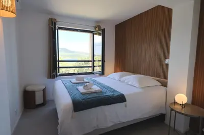 a bedroom with a large bed with a large window at U Mare - T2 cabine avec vue mer, plage & piscine in Pianottoli-Caldarello