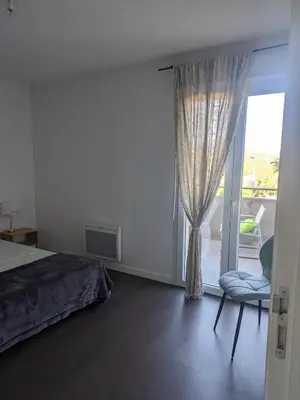 a bedroom with a bed and a window and a chair at Joli cocon à Ajaccio avec terrasse vue mer in Ajaccio