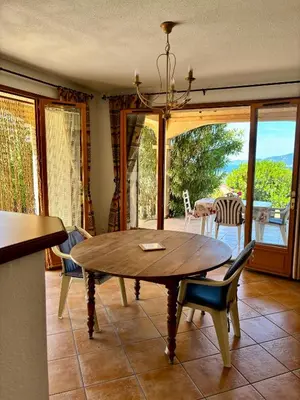 a dining room with a wooden table and chairs at Grand appartement vue mer Agosta in Albitreccia