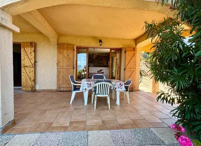 a patio with a table and chairs on it at Grand appartement vue mer Agosta in Albitreccia