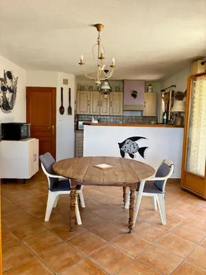a kitchen with a table and chairs in a kitchen at Grand appartement vue mer Agosta in Albitreccia