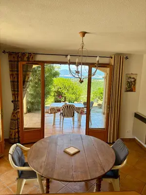 a dining room with a table and a view of the ocean at Grand appartement vue mer Agosta in Albitreccia