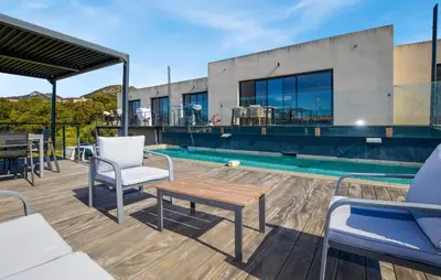 a patio with chairs and a table next to a pool at Villa Spacieuse Proche Plages in Vardiola