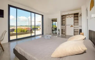 a bedroom with a large bed and a large window at Villa Spacieuse Proche Plages in Vardiola