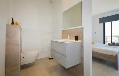 a bathroom with a sink and a toilet and a bed at Villa Spacieuse Proche Plages in Vardiola