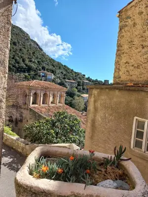 a stone planter with flowers on the side of a building at Les voûtes de Pascaline, vue mer et montagne, Lama in Lama