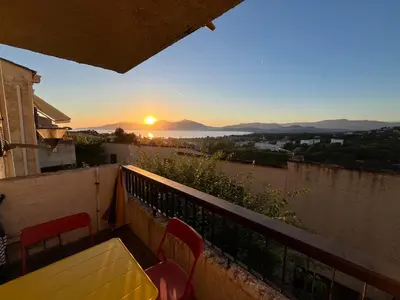 a balcony with a yellow table and chairs and the sunset at Charmant 2 pièces avec vue sur mer exceptionnelle à Porticcio, Corse du Sud in Grosseto-Prugna