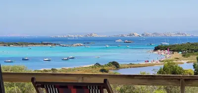 a bench overlooking a beach with boats in the water at Bonifacio accès mer et golf - vue exceptionnelle in Bonifacio