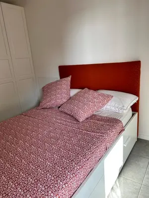 a bed with a red headboard and pillows on it at Porticcio Agosta in Albitreccia