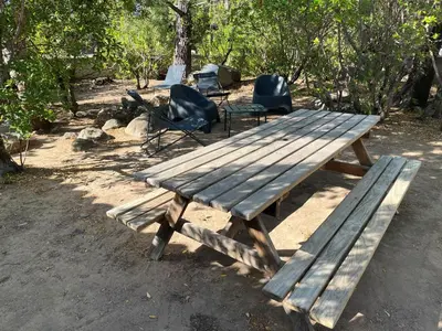 a wooden picnic table and chairs in the woods at Mini villa plage de saint cyprien in Lecci