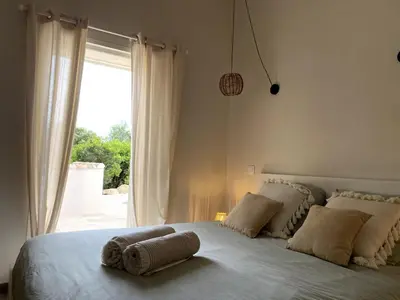 a bedroom with a large bed with a window at Villa Porto Vecchio, calme avec piscine in Porto-Vecchio