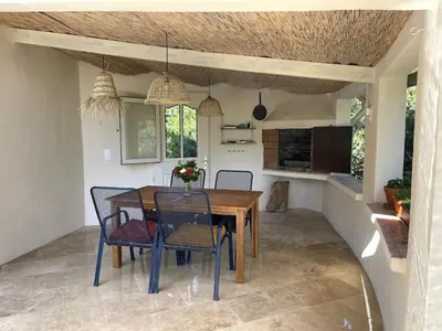 a kitchen and dining room with a wooden table and chairs at Villa Porto Vecchio, calme avec piscine in Porto-Vecchio