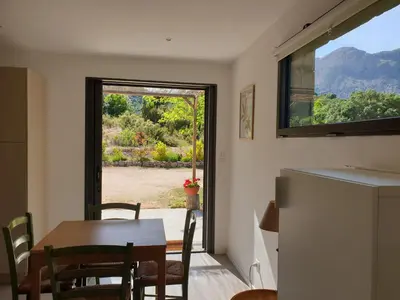 a kitchen and dining room with a table and a window at Gozzi Mandriolu in Afa