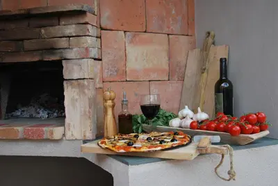 a pizza on a cutting board with tomatoes and a bottle of wine at Villa Madra in Bonifacio