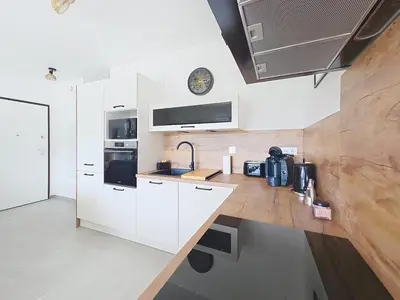 a kitchen with white cabinets and a wooden counter top at appartement T2 rive sud porticcio vue mer in Pietrosella