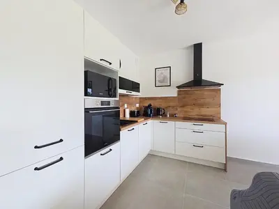 a kitchen with white cabinets and a stove top oven at appartement T2 rive sud porticcio vue mer in Pietrosella