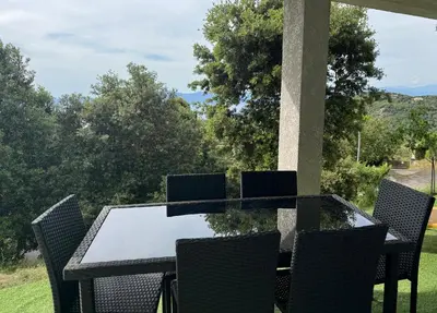 a glass table and chairs on a patio with a view at RANDOS à 15 mn de la plage COTI CHIAVARI Vue exceptionnelle Appart indépendant 3 ch in Coti-Chiavari