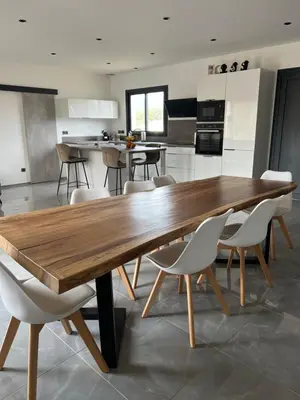 a large wooden table in a kitchen with white chairs at Maison 2 chambres in Figari
