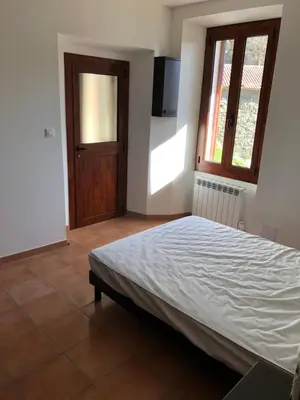 a bedroom with a bed and a window and a television at Maison de village Frasseto in Frasseto