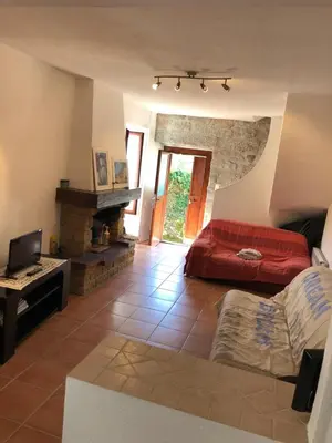 a living room with a red bed and a fireplace at Maison de village Frasseto in Frasseto