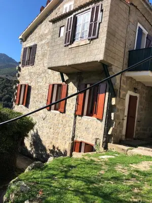 a stone house with red doors and windows at Maison de village Frasseto in Frasseto