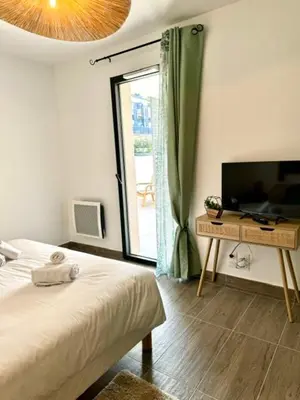 a bedroom with a bed and a television and a table at T2 confort - résidence privée in Propriano