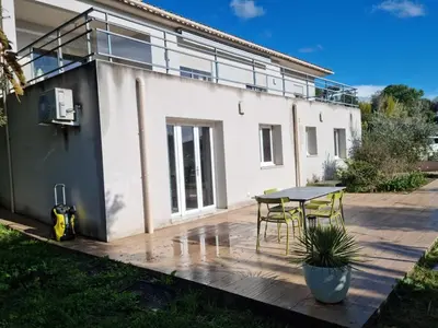 a blue swimming pool with a chair in front of a house at T2, rez de villa avec piscine in Afa