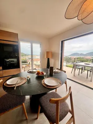 a dining room with a table and chairs with a view at Appartement CASA VISTA splendide vue sur le Golfe in Porto-Vecchio