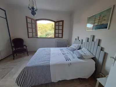 a bedroom with a large white bed with a window at Spacieuse villa avec vue exceptionnelle in Piana