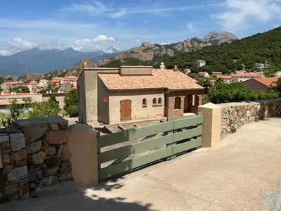 a house with a fence and mountains in the background at Spacieuse villa avec vue exceptionnelle in Piana