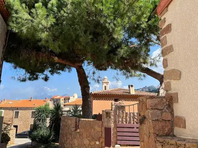 a house with a tree in front of a fence at Spacieuse villa avec vue exceptionnelle in Piana