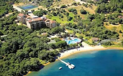 an aerial view of a resort with a boat on a beach at Luxueux T4 de 100m2 avec roof top, piscine et plage in Pianottoli-Caldarello