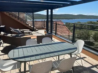 a table and chairs on a balcony with a view of the water at Luxueux T4 de 100m2 avec roof top, piscine et plage in Pianottoli-Caldarello
