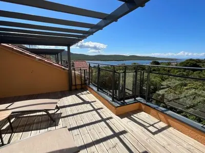 a balcony with chairs and a view of the water at Luxueux T4 de 100m2 avec roof top, piscine et plage in Pianottoli-Caldarello