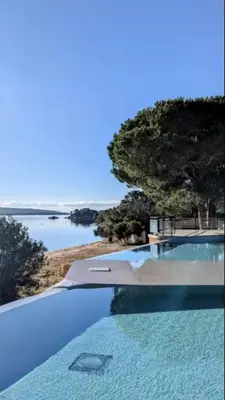 a swimming pool with a view of a body of water at Luxueux T4 de 100m2 avec roof top, piscine et plage in Pianottoli-Caldarello
