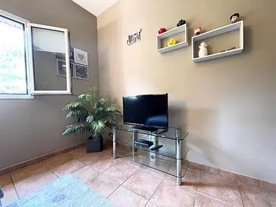 a living room with a television on a table at Délice du maquis Corse in Porto-Vecchio