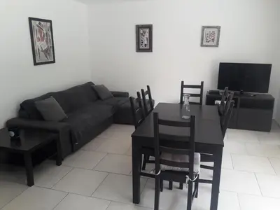 a living room with a black couch and a table at Briloc Appartements Pietrosella à 50m de la plage in Pietrosella