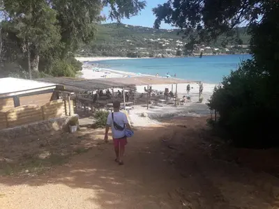 a man walking down a dirt path towards a beach at Briloc Appartements Pietrosella à 50m de la plage in Pietrosella
