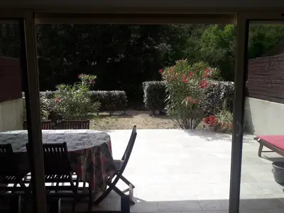 a patio with a table and chairs and some flowers at Briloc Appartements Pietrosella à 50m de la plage in Pietrosella