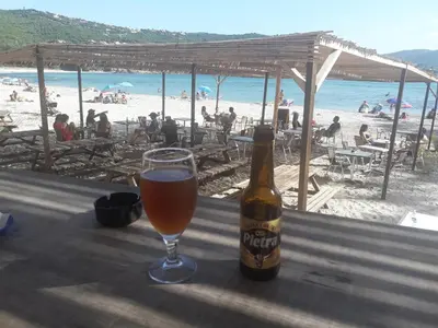 a bottle of beer sitting on a table next to a glass at Briloc Appartements Pietrosella à 50m de la plage in Pietrosella