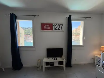 a living room with a tv and two windows at L'Ancrage - TV, Vue sur le port, Wi-Fi in Bonifacio