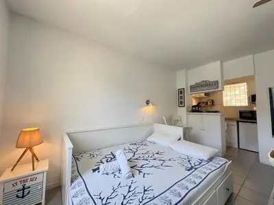 a bedroom with a white bed and a kitchen at L'Ancrage - TV, Vue sur le port, Wi-Fi in Bonifacio