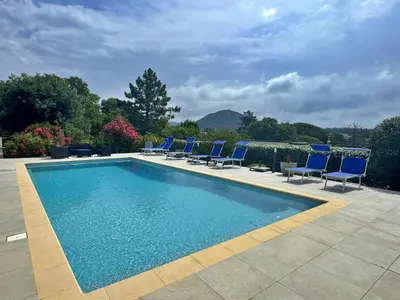 a swimming pool with blue chairs next to at VILLA GIULIA - Piscine - Jacuzzi - 4 Chambres in Porto-Vecchio