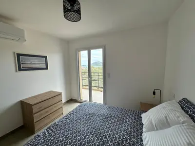 a white bedroom with a bed and a window at Appartement 2-4 pers vue mer proche port in Porto-Vecchio