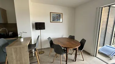 a dining room with a wooden table and chairs at Appartement 2-4 pers vue mer proche port in Porto-Vecchio