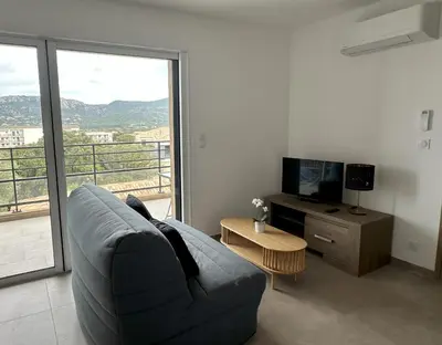 a living room with a blue couch and a television at Appartement 2-4 pers vue mer proche port in Porto-Vecchio
