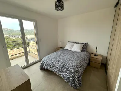 a bedroom with a bed and a large window at Appartement 2-4 pers vue mer proche port in Porto-Vecchio