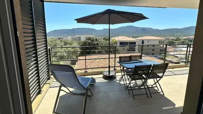 a balcony with a table and chairs and an umbrella at Appartement 2-4 pers vue mer proche port in Porto-Vecchio