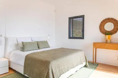 a white bedroom with a bed and a mirror at Villa Lume Di Palombaggia in Musoleu