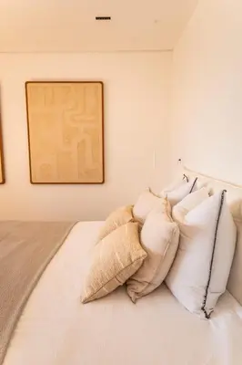 a bed with white pillows and a painting on the wall at Villa Lume Di Palombaggia in Musoleu